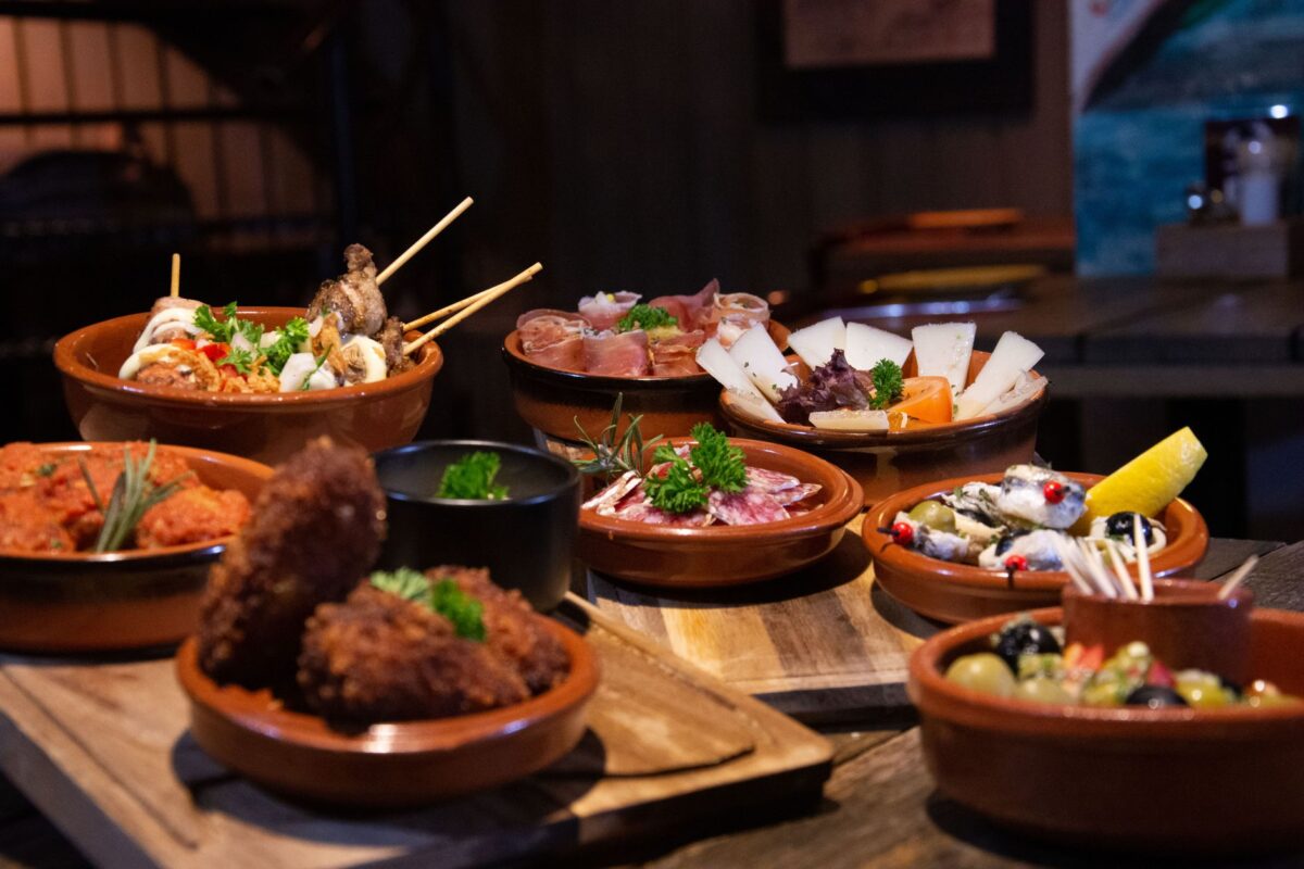 An inviting spread of various tapas dishes elegantly arranged in a cozy indoor restaurant ambiance.